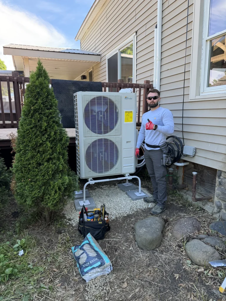 Astello LLC technician next to a newly installed Senville Aura series multi-zone mini-split heat pump condenser on a ground stand in Ballston Spa, NY.