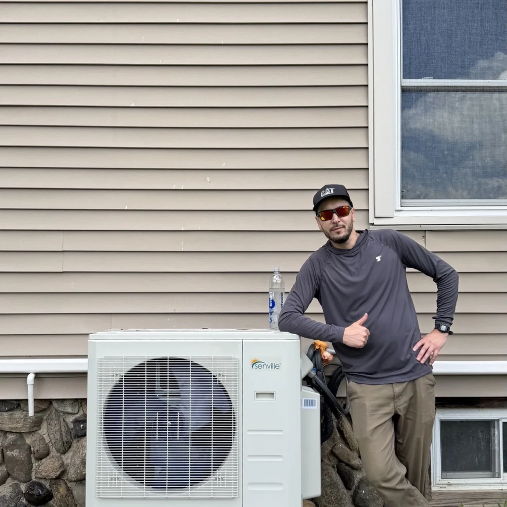 Technician beside a newly installed Senville cold-climate heat pump, Capital District, NY