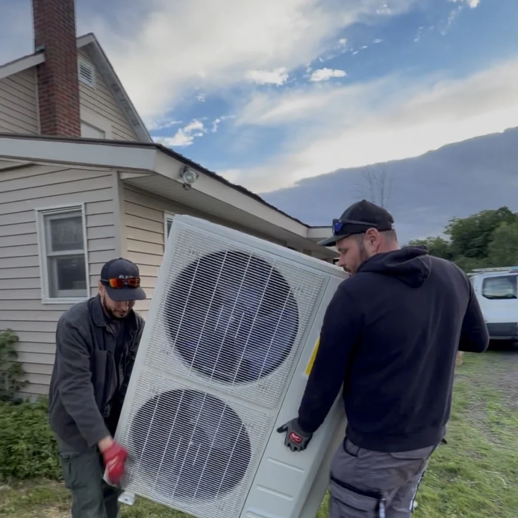 HVAC technicians moving a large mini-split outdoor condenser
